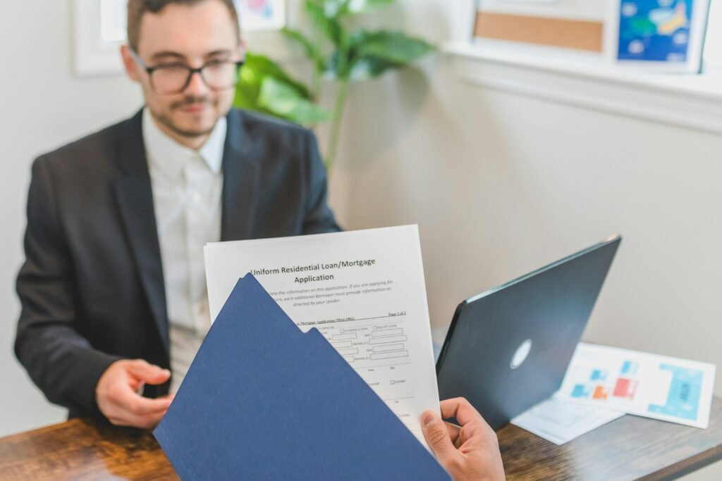 PERSONAL LOAN RATE Mortgage broker and client discussing loan application with documents on table.