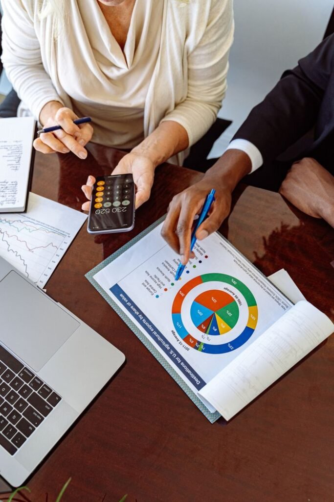 LOAN MORTGAGE CALCULATOR Two business professionals discussing financial documents and strategies at an office desk.