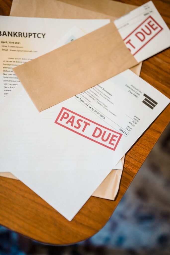 PERSONAL LOAN DEBT CONSOLIDATION Photograph showing past due and bankruptcy documents on a wooden table.