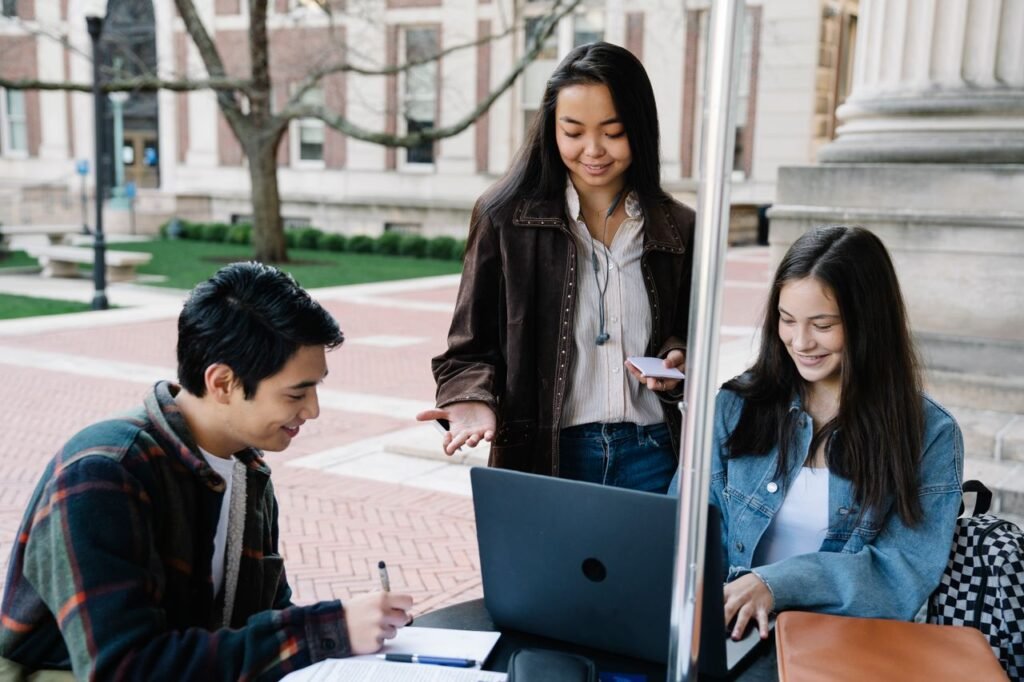 STUDENT LOAN Group of university students collaborating and studying together in an outdoor setting.