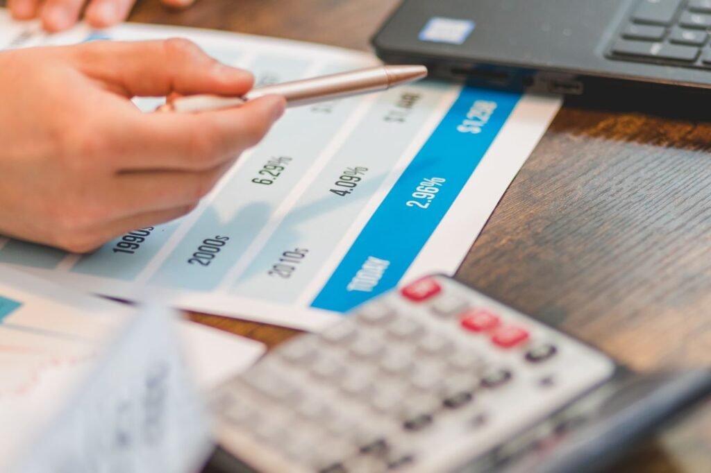 LOAN FOR SMALL BUSINESS Close-up of a hand using a ballpen and calculator to analyze interest rates on a chart.