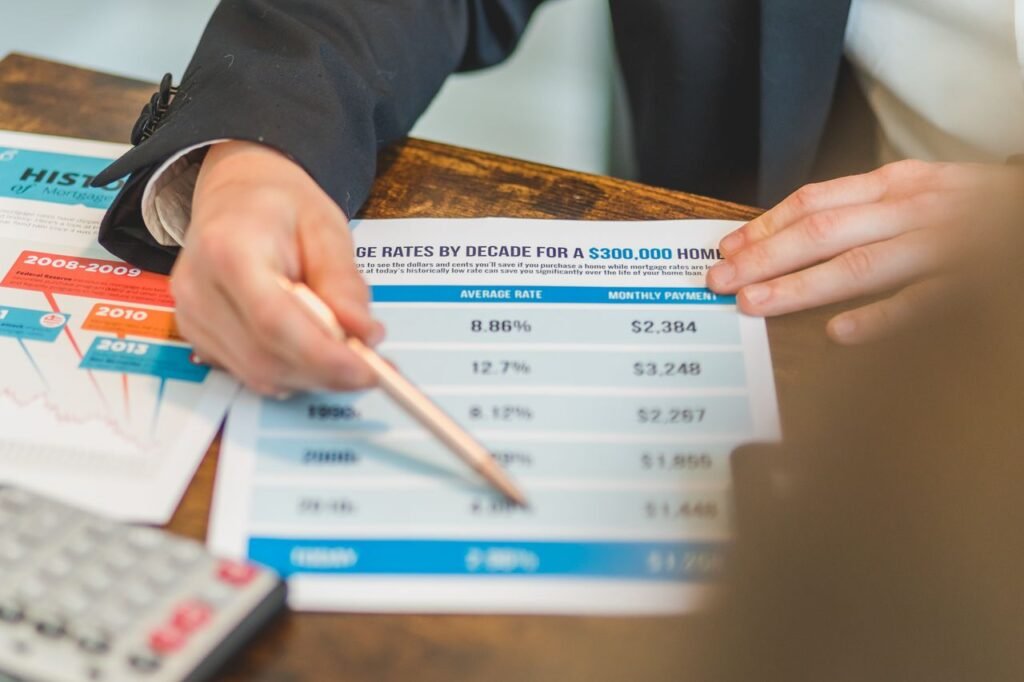 LOAN MORTGAGE RATES A close-up of hands analyzing mortgage rate documents with a pen and calculator in a business setting.