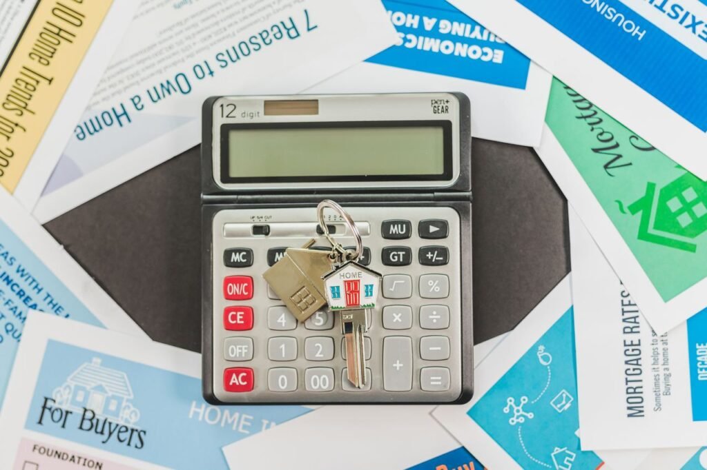 AUTO LOAN CALCULATOR Calculator with keys and real estate documents symbolizes home buying finances.